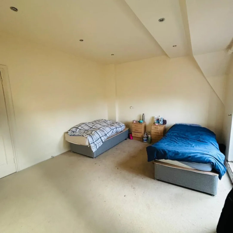 Bedroom with two beds, neutral walls, and sloped ceiling.