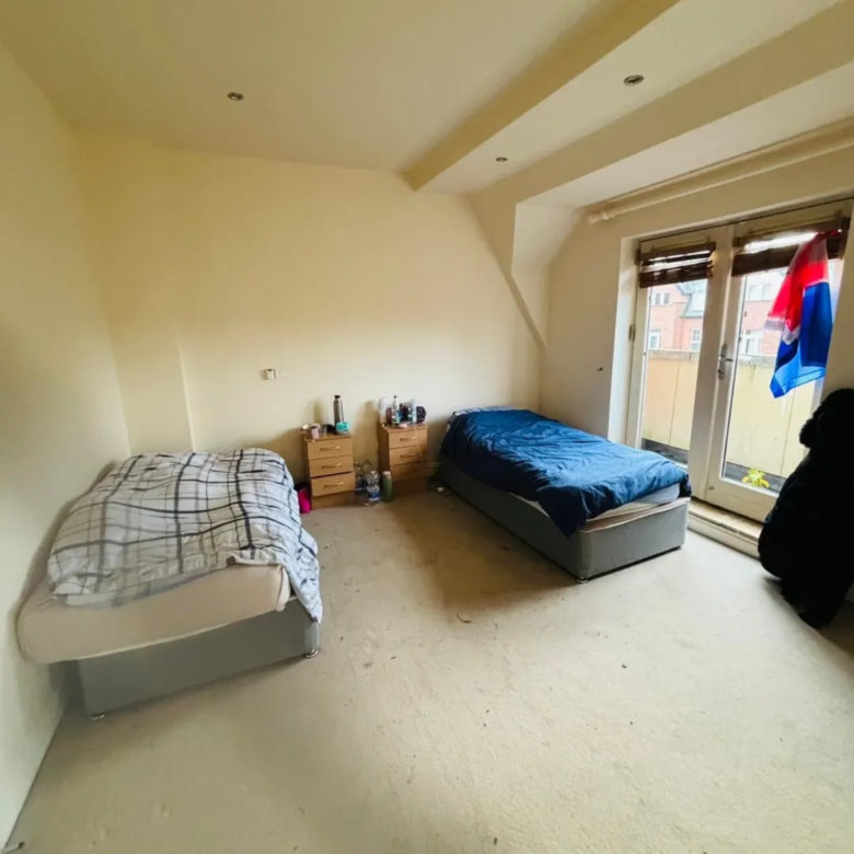 Bedroom with two single beds, bedside tables, and a door leading to a balcony.