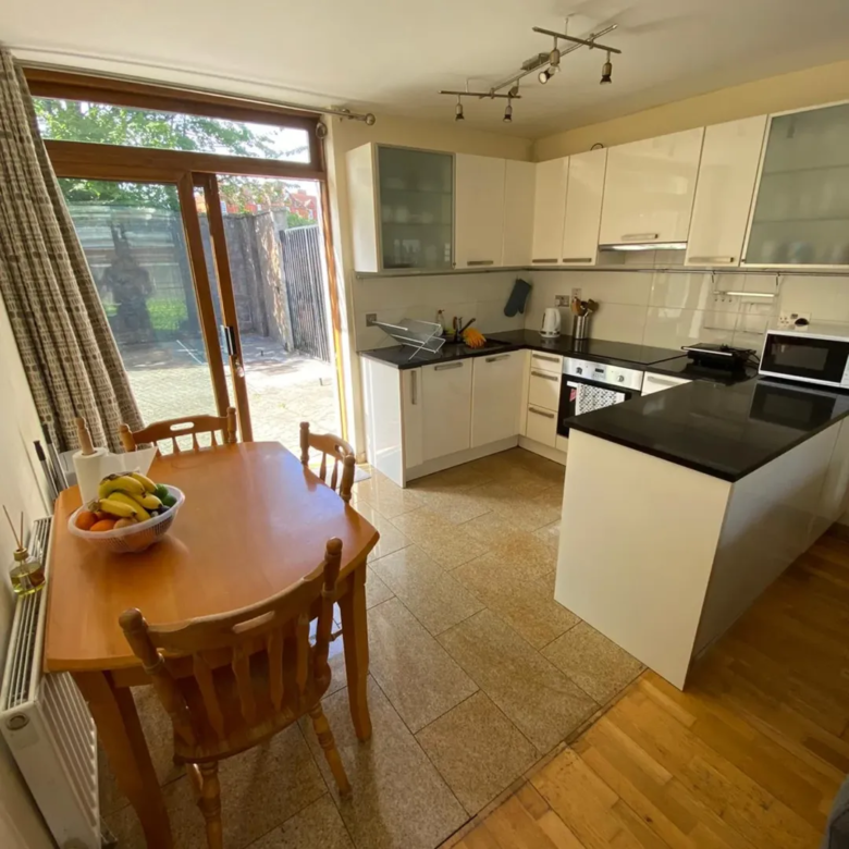 Bright kitchen with table, chairs, white cabinets, and sliding glass doors to a garden.