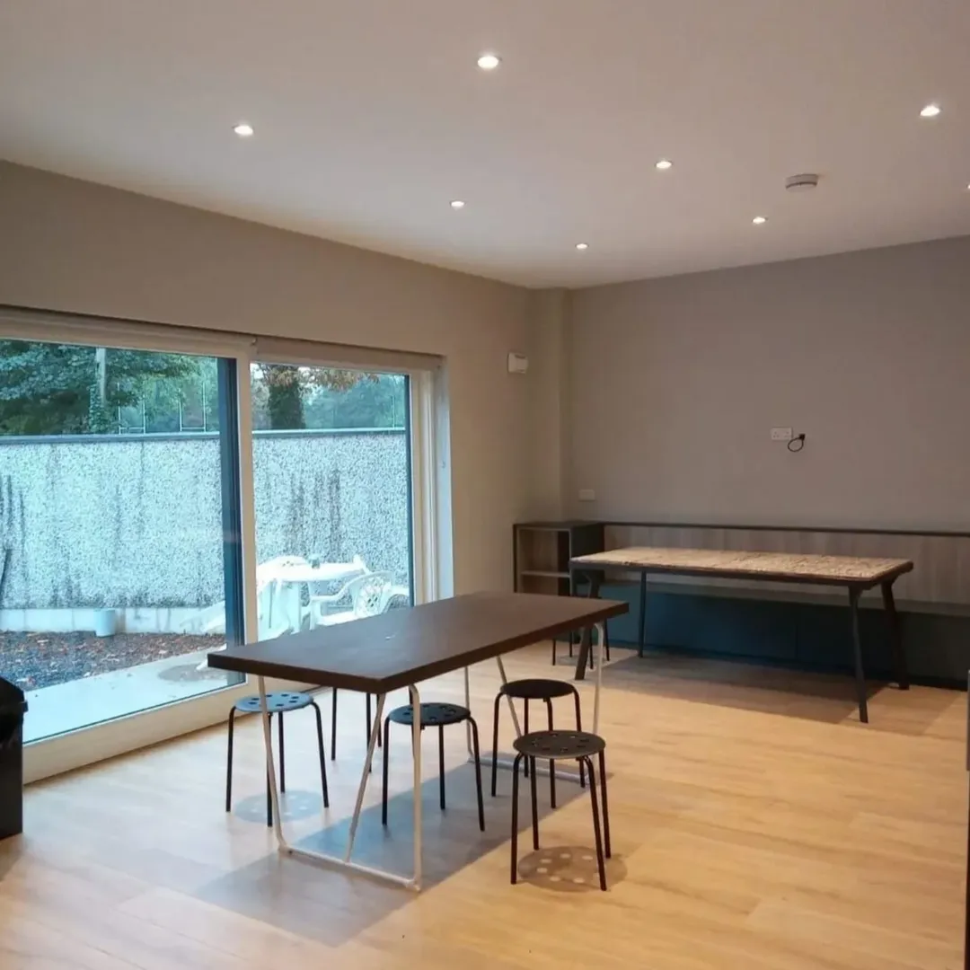 Bright room with tables, stools, and large sliding glass doors to outside.