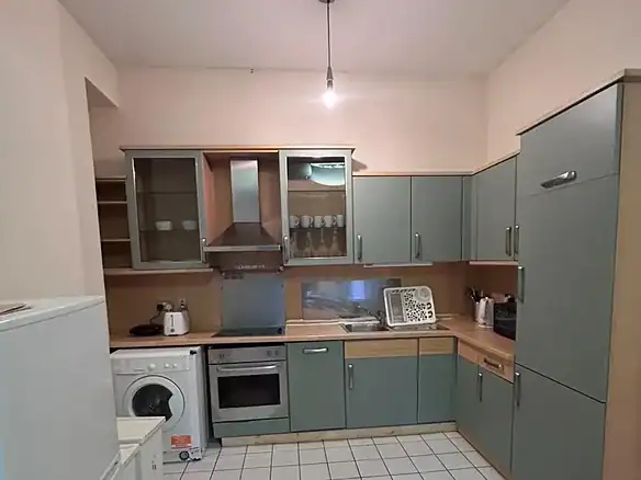 Compact kitchen with gray cabinets, white appliances, and tile flooring.
