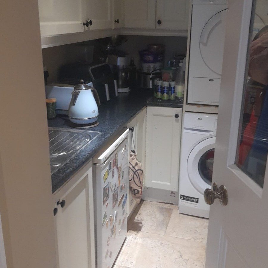 Compact kitchen with white cabinets, appliances, and a small refrigerator.