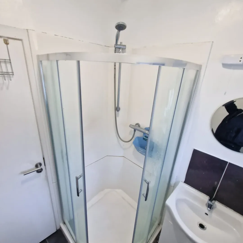 Corner shower unit with glass doors in a small bathroom.