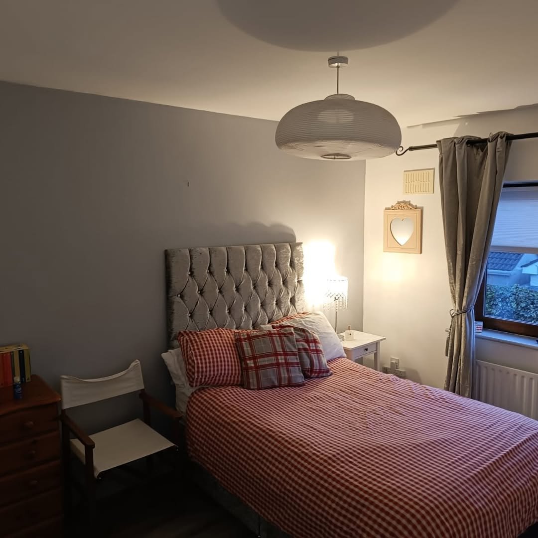Cozy bedroom with grey walls, red checkered bedding, and soft lighting.