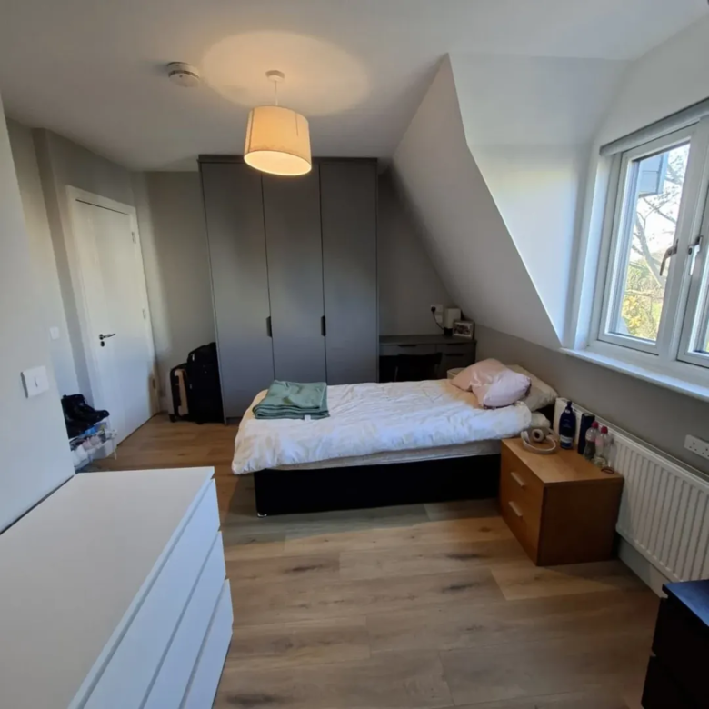 Cozy bedroom with bed, wardrobe, and window in neutral tones.