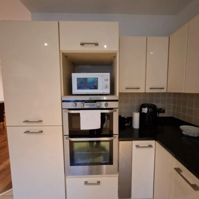 Kitchen with built-in microwave and oven in cream cabinetry.