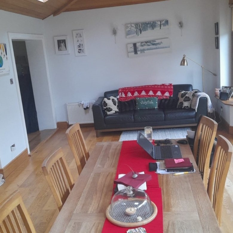 Dining room with wooden table, chairs, sofa, and artwork on the wall.