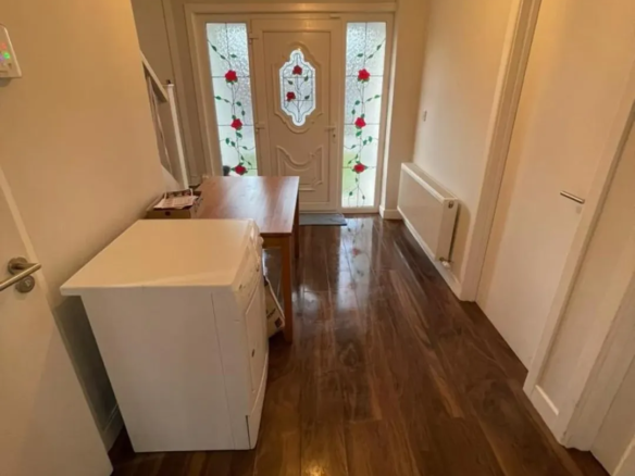 Entryway with wood floor, white cabinet, table, and stained glass front door.