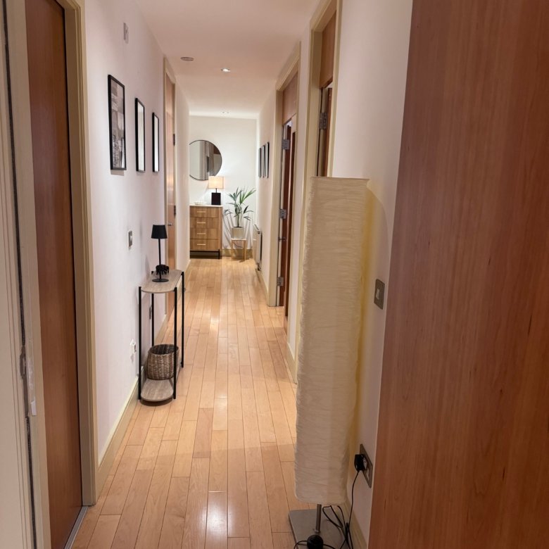 Hallway with hardwood floors, white walls, and decorative console table.