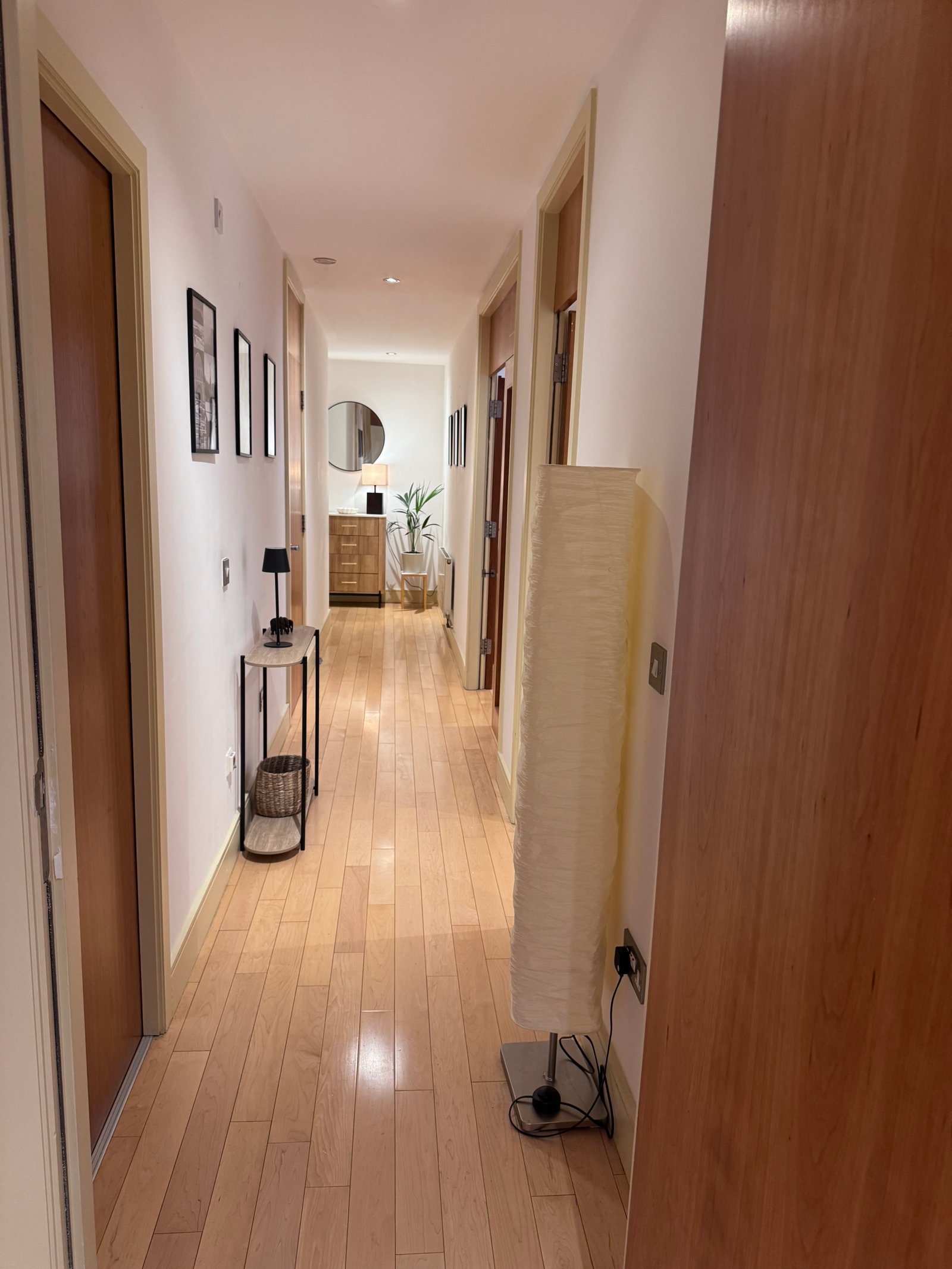 Hallway with hardwood floors, white walls, and decorative console table.