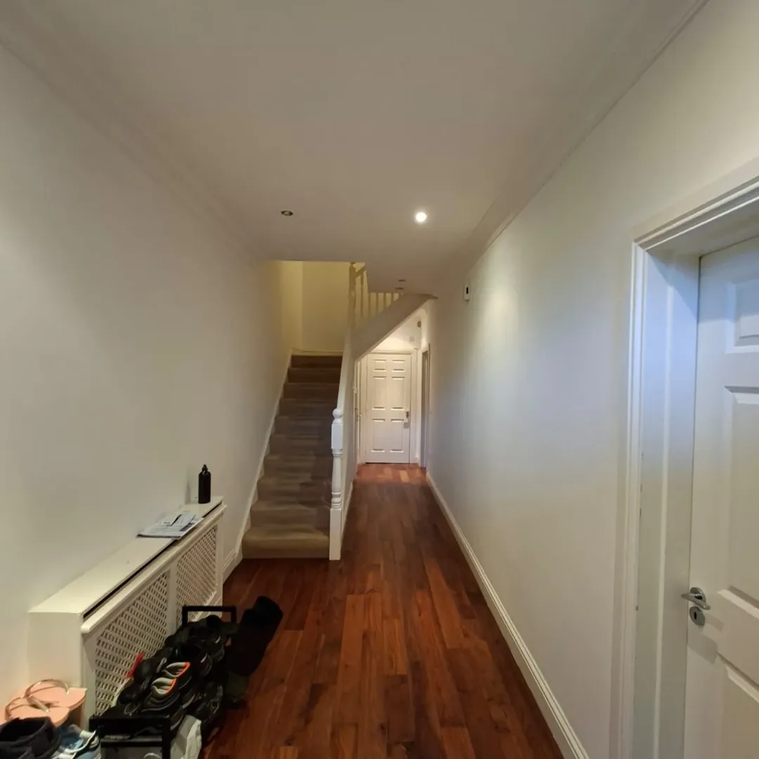 Hallway with hardwood floors, stairs, and white walls. Minimalist interior design.