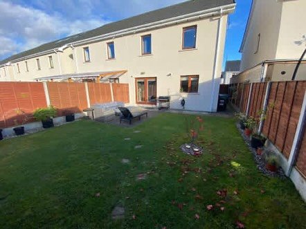 Backyard with grass, fence, patio furniture, and house exterior.