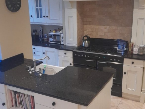 Kitchen with black countertops, white cabinets, and island with wine rack.
