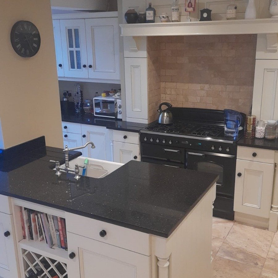 Kitchen with black countertops, white cabinets, and island with wine rack.