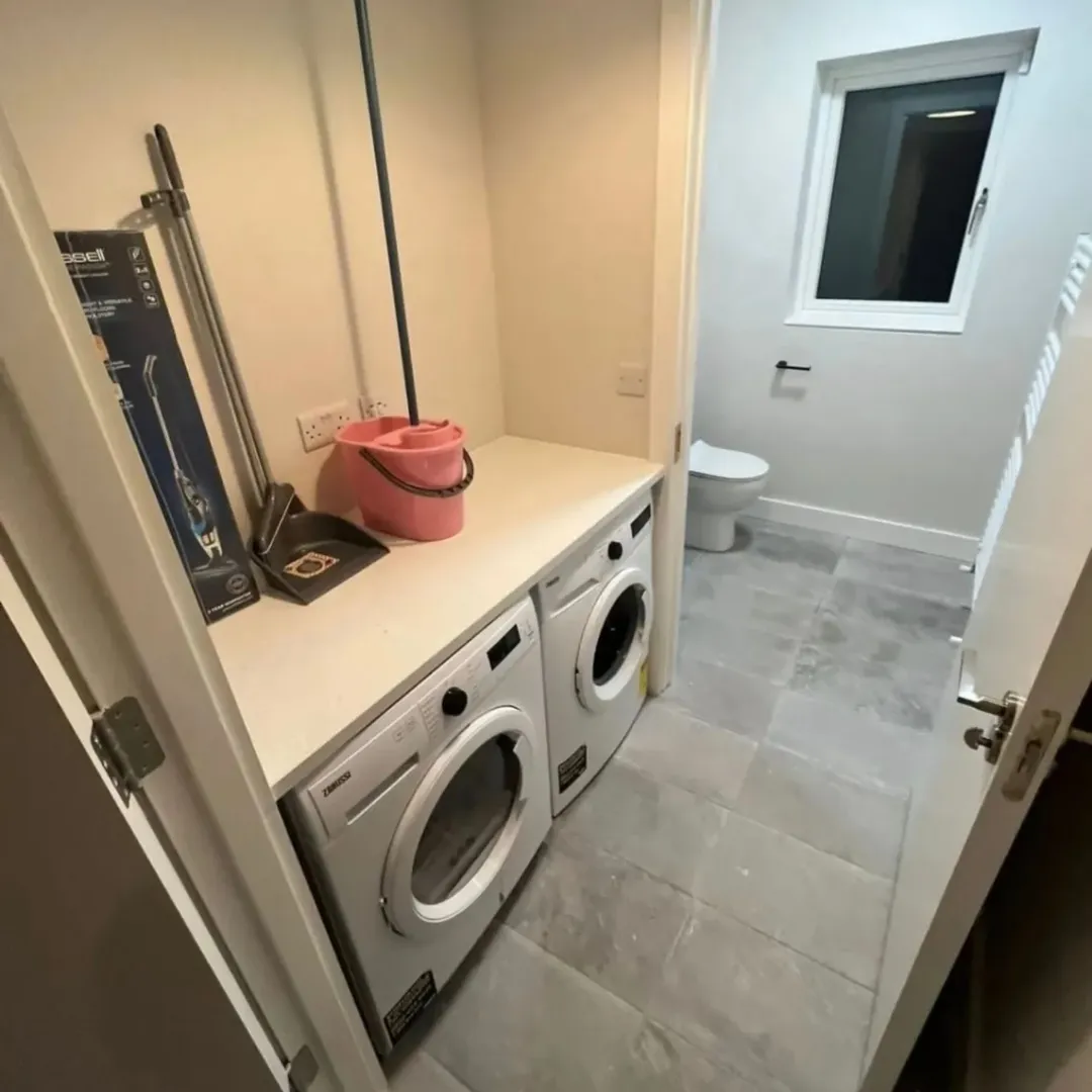 Laundry room with washer, dryer, cleaning supplies, and visible toilet area.