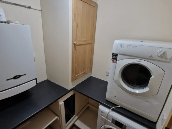 Laundry room with washing machine, dryer, storage, and boiler.