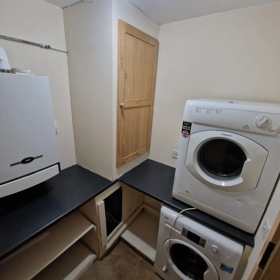 Laundry room with washing machine, dryer, storage, and boiler.