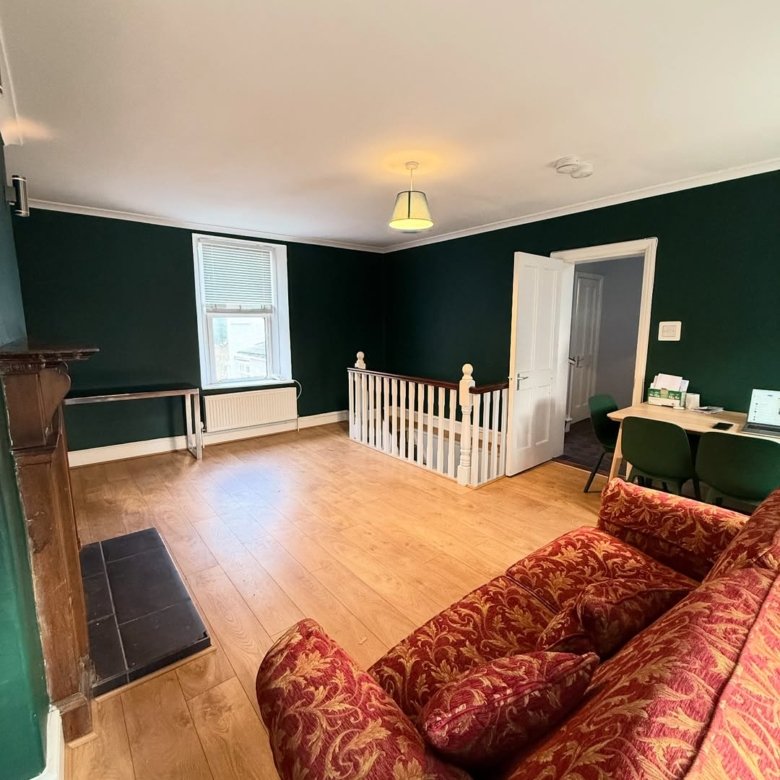 Living room with red sofa, dark green walls, and staircase.