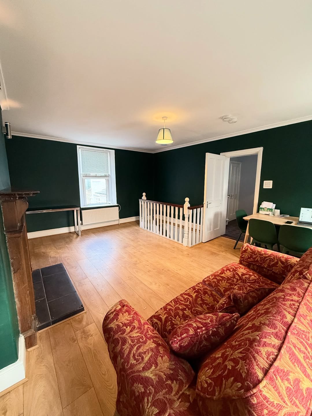 Living room with red sofa, dark green walls, and staircase.