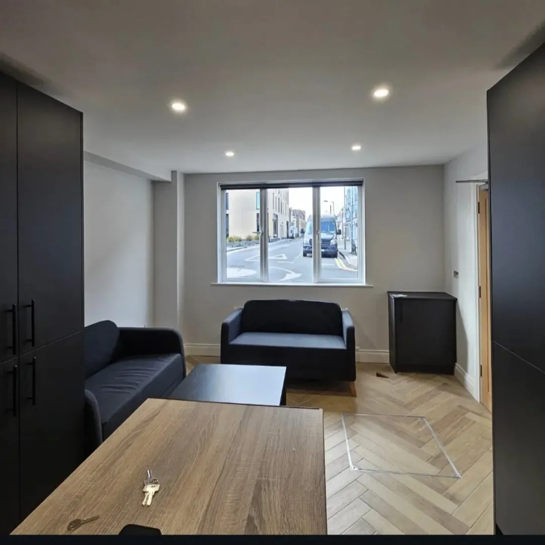 Modern apartment living room with sofas, table, and herringbone floor.