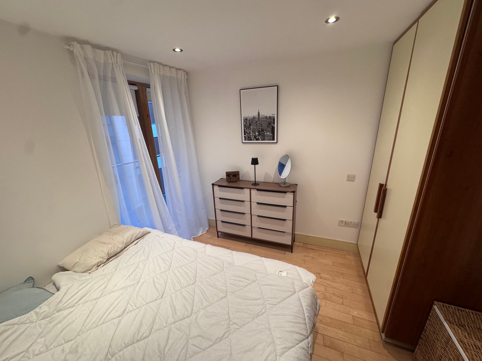 Cozy bedroom with bed, dresser, and wardrobe in a modern apartment interior.