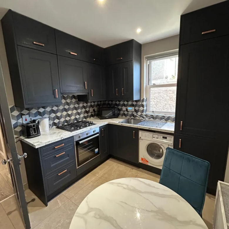 Modern black kitchen with marble countertops and copper hardware.