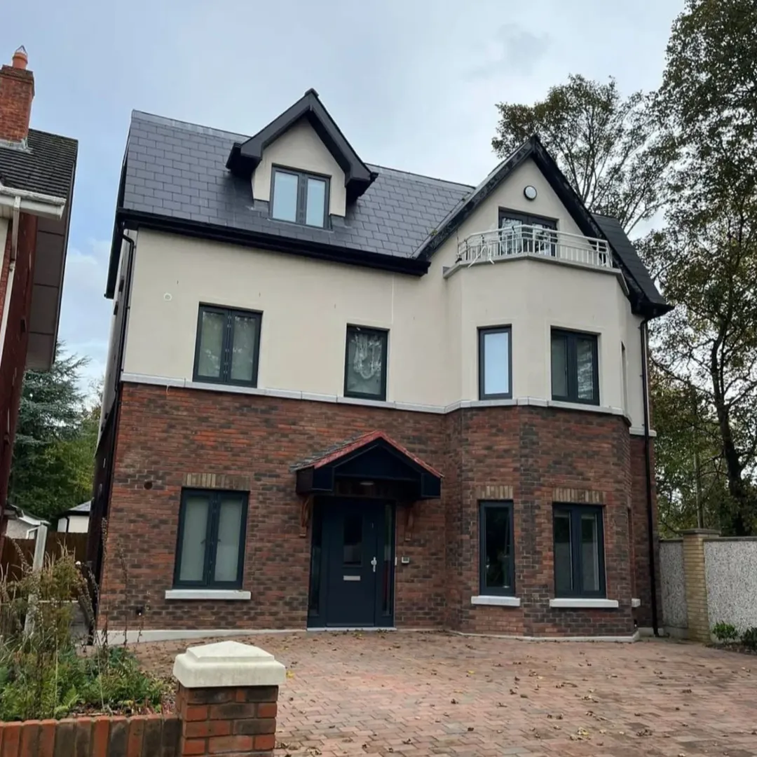 Modern two-story house with brick and stucco exterior, dark roof, and gray window frames.