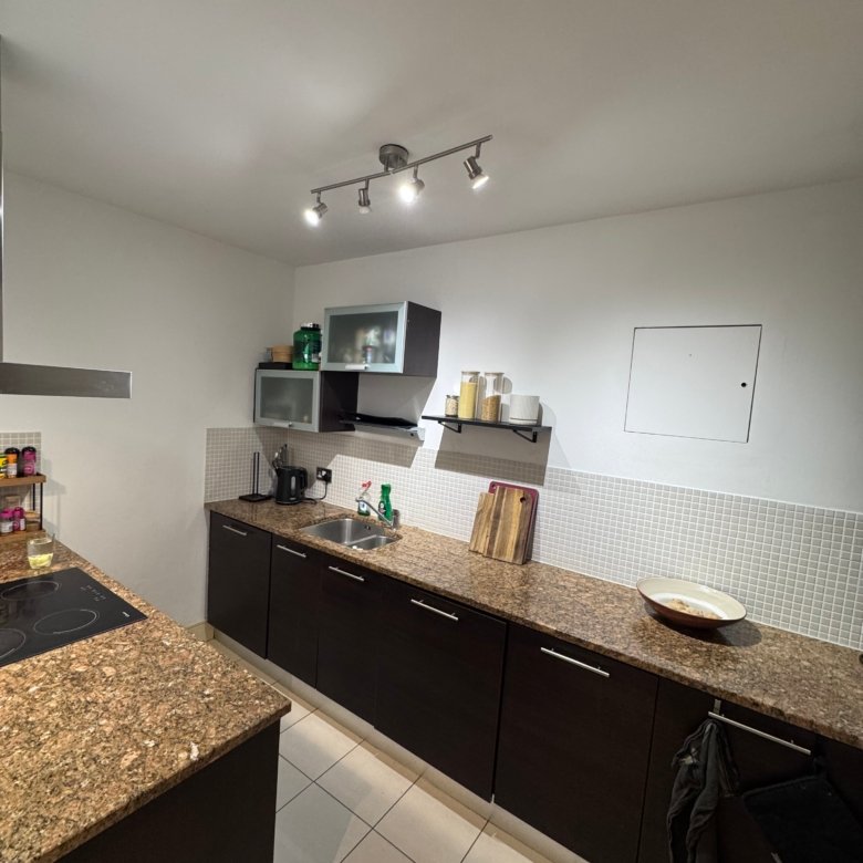 Modern kitchen with dark cabinets and granite countertops, tiled backsplash.