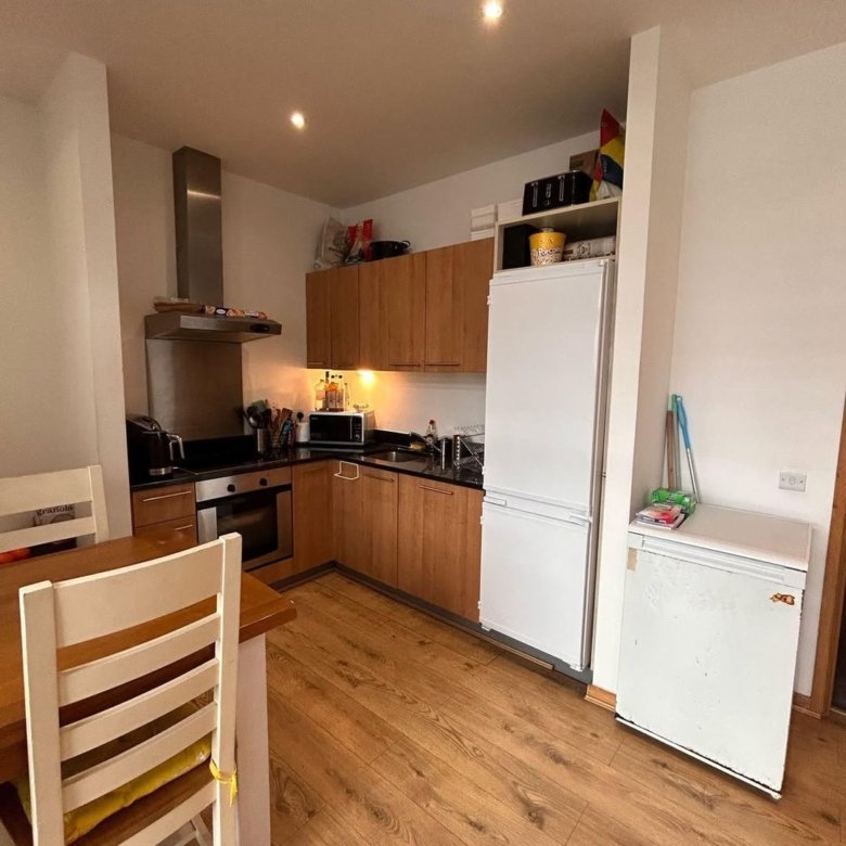 Modern kitchen with wooden cabinets, stainless steel appliances, and light wood flooring.
