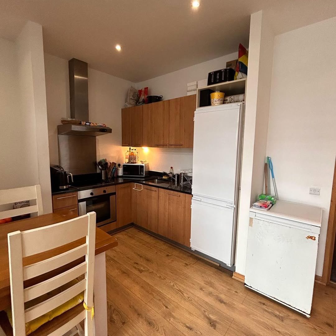 Modern kitchen with wooden cabinets, stainless steel appliances, and light wood flooring.