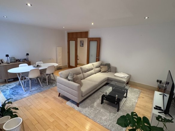 Modern living room: couch, coffee table, wood floors, and plants.