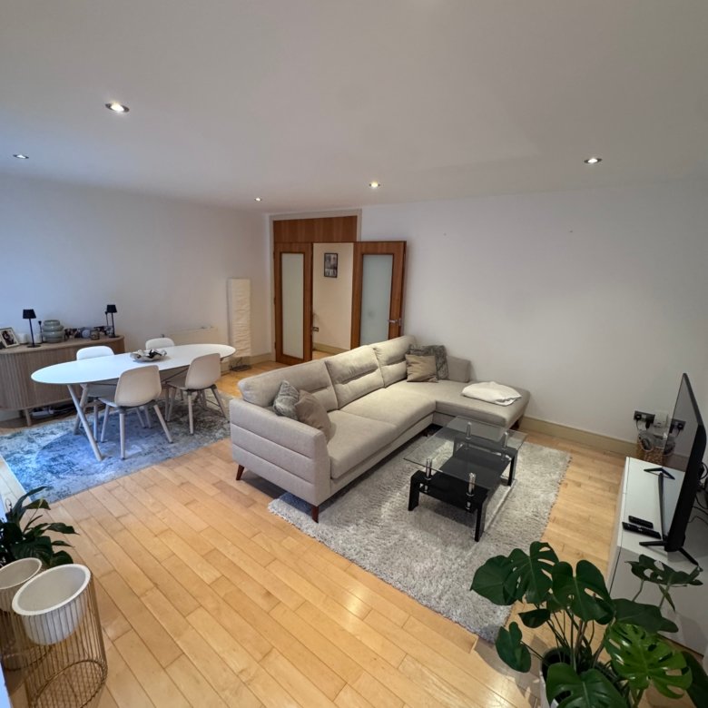 Modern living room: couch, coffee table, wood floors, and plants.