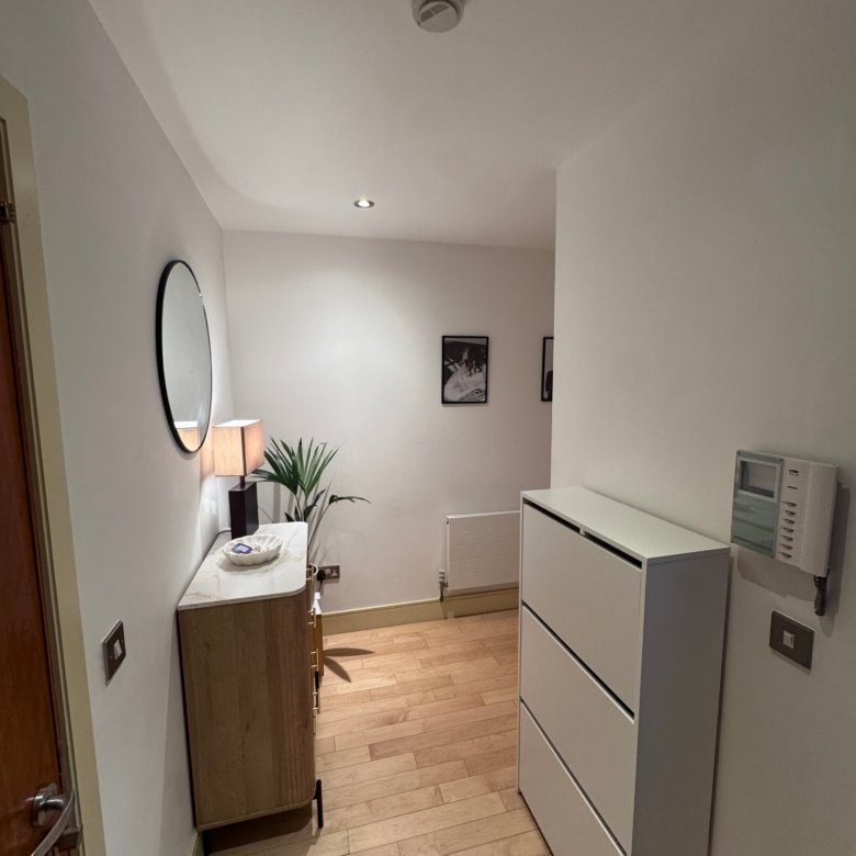 Modern room with white walls, wood floor, round mirror, and cabinet.
