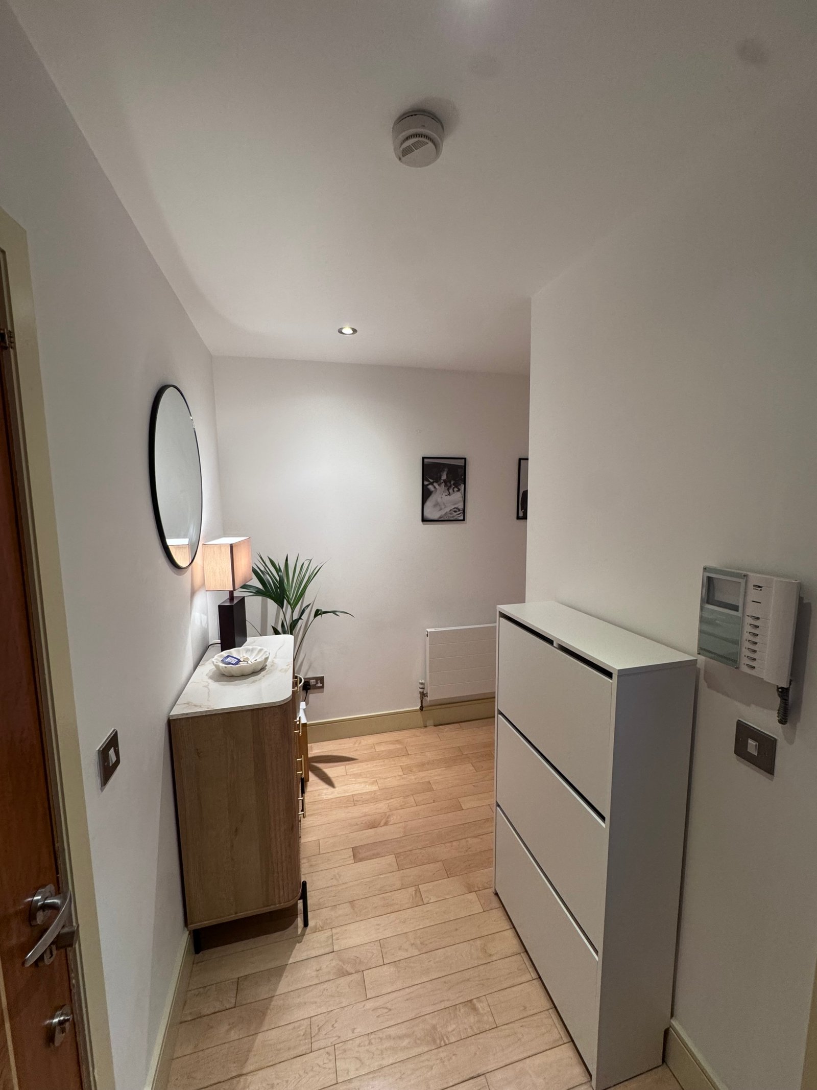 Modern room with white walls, wood floor, round mirror, and cabinet.