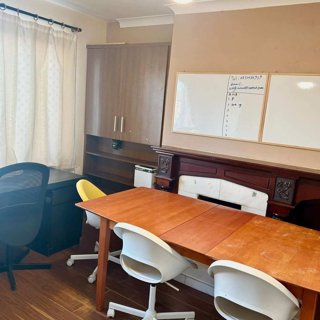 Office space with table, chairs, whiteboard with text, and storage units.