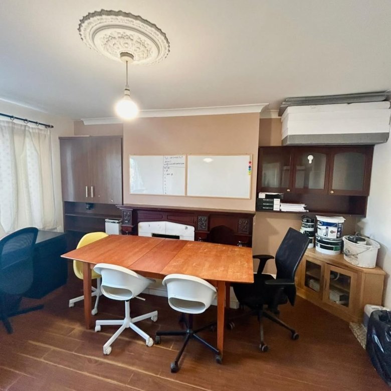 Office space with table, chairs, whiteboards, cabinets, and paint cans. Interior design, working environment.