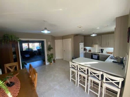 Bright, open kitchen and dining area with island seating and a view into another room.