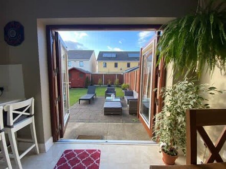 Open folding doors leading to a patio with lounge chairs and garden.