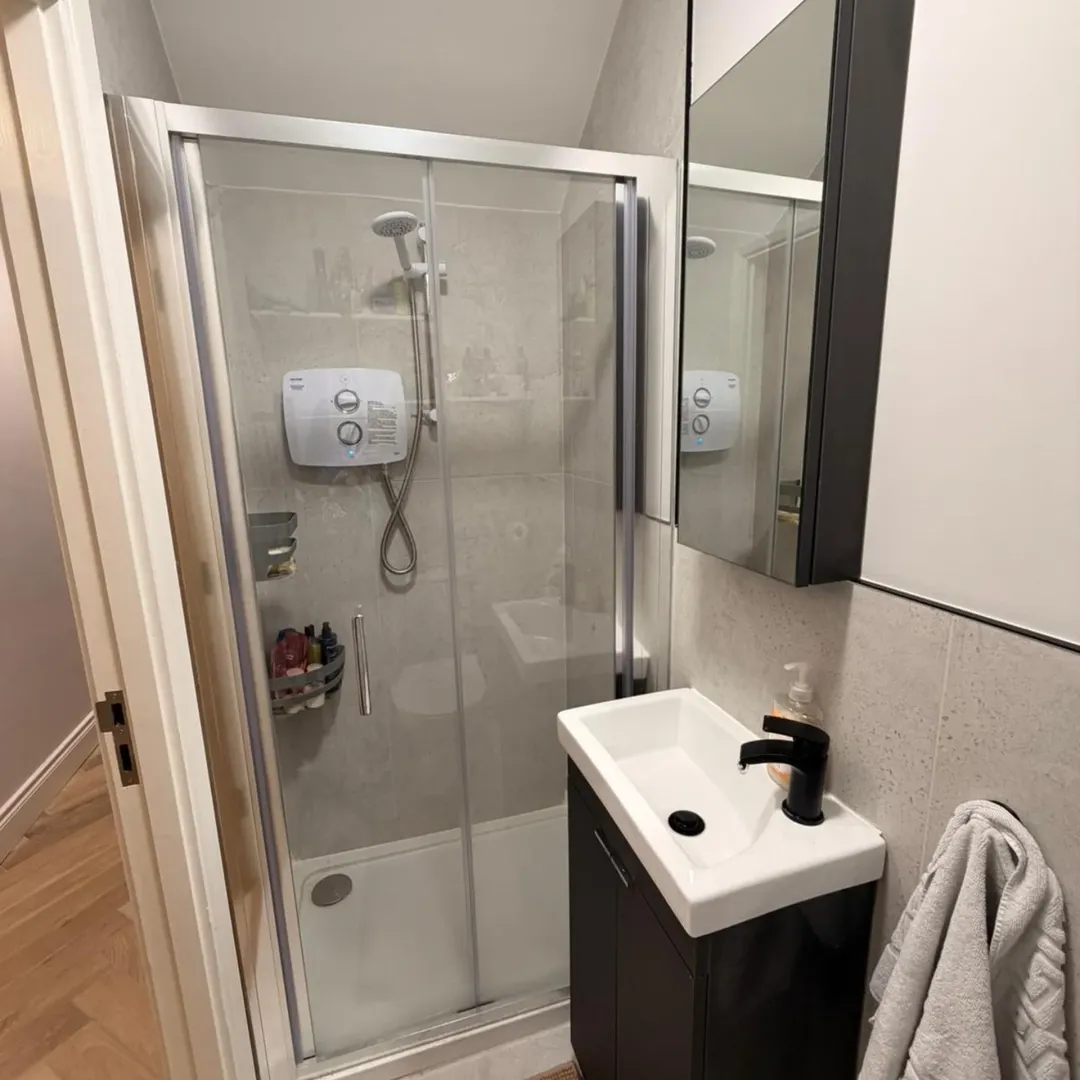 Small bathroom with shower, sink, and mirrored cabinet. Modern, compact design.