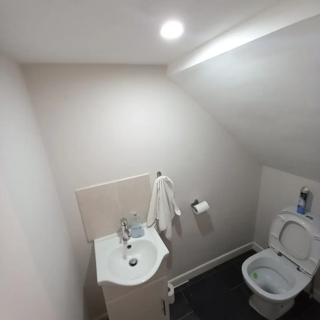 Small bathroom with toilet, sink, and angled ceiling.