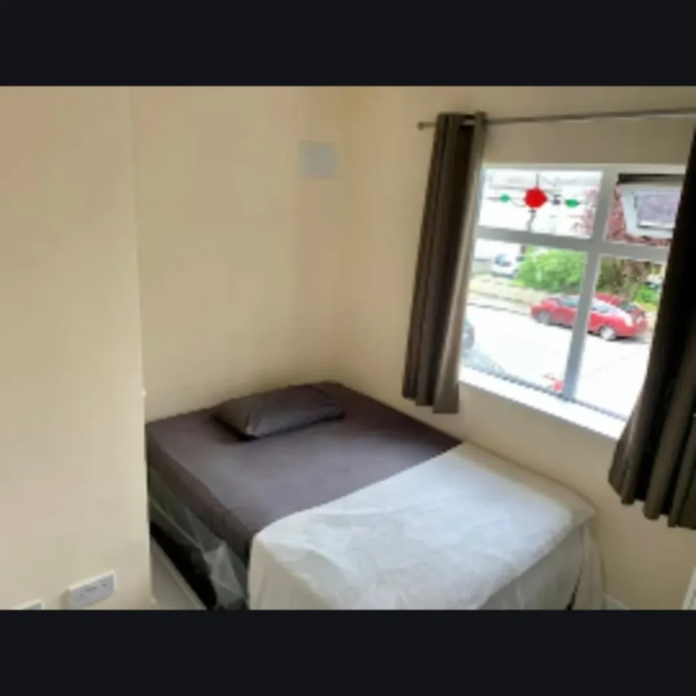 Small bedroom with single bed, window, and neutral decor. Cozy, compact living space.