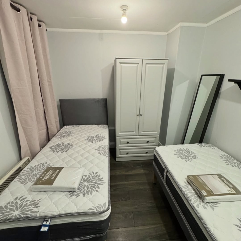 Cozy room with two twin beds, wardrobe, and mirror. Neutral tones create a simple, functional space.