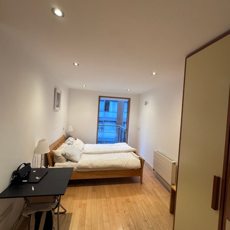 Cozy studio apartment with bed, desk, and window. Modern interior design.