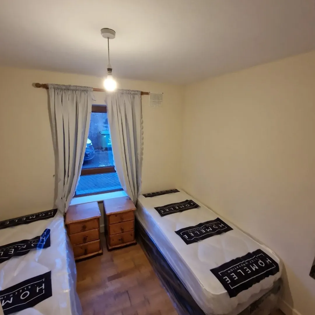 Bedroom with two twin beds, window, and nightstands. Neutral color scheme.