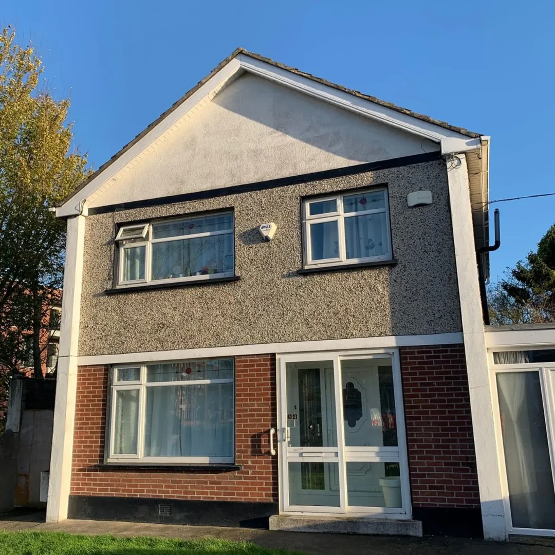 Two-story house with brick and stucco exterior, white door and window frames, blue sky