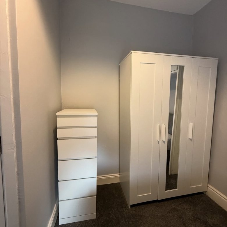 White wardrobe and chest of drawers in a bedroom corner.