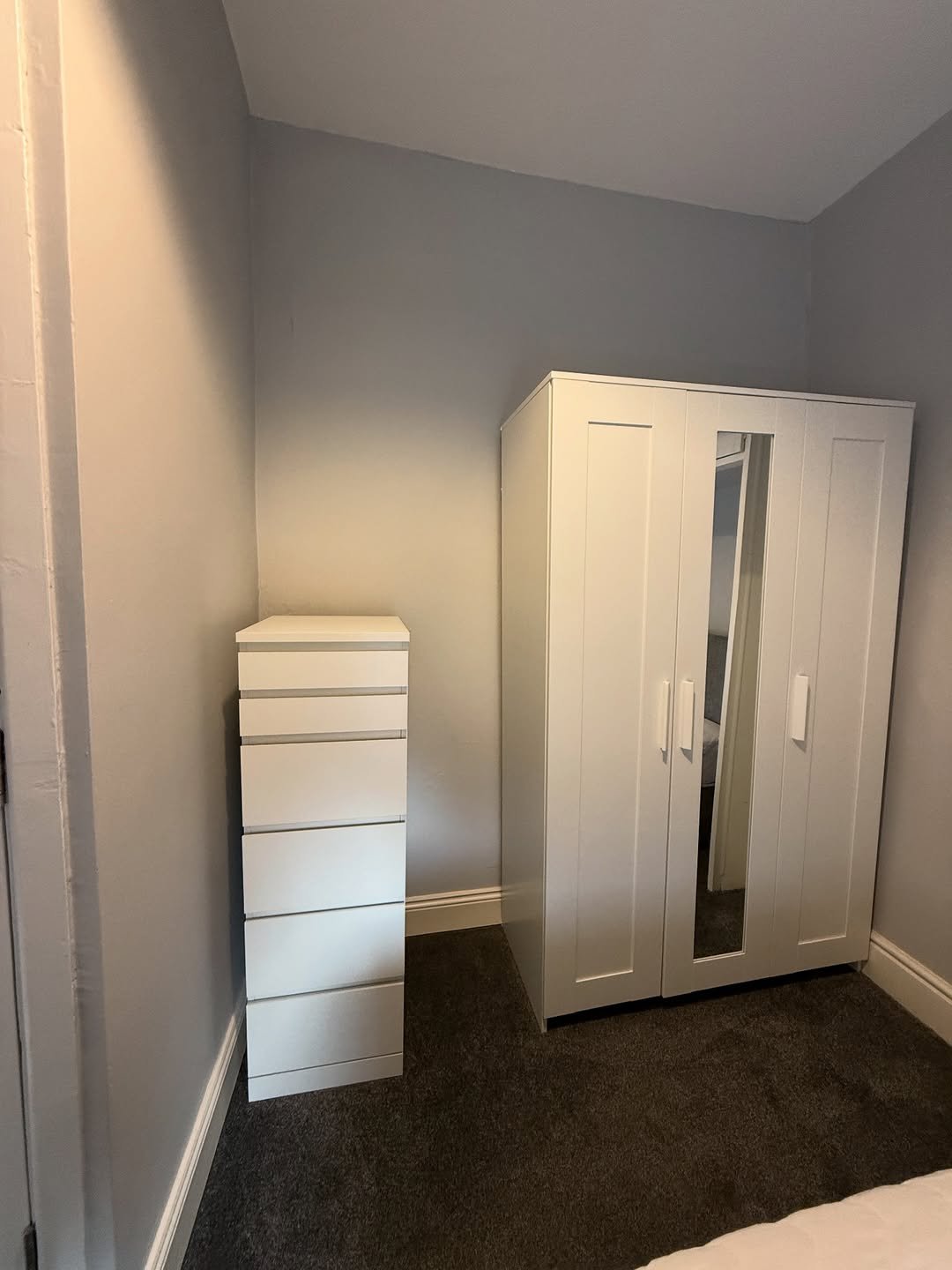White wardrobe and chest of drawers in a bedroom corner.