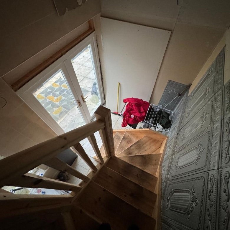 Wooden stairs leading to a door with patterned paving outside.