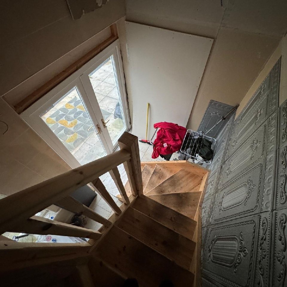 Wooden stairs leading to a door with patterned paving outside.