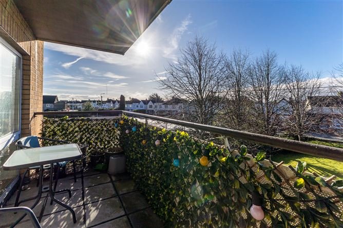 Apartment balcony with table, chairs, and privacy screen overlooking a residential street.